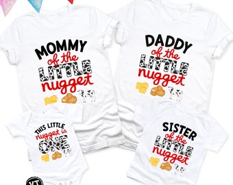 May include: White t-shirts with the text "Mommy of the Little Nugget", "Daddy of the Little Nugget", and "Sister of the Little Nugget" in black with a cow print design. A white onesie with the text "This Little Nugget is One" in black with a cow print design.