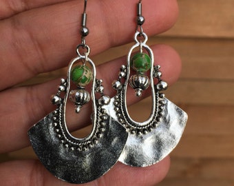May include: Silver dangle earrings with a green stone bead and a fan-shaped design.
