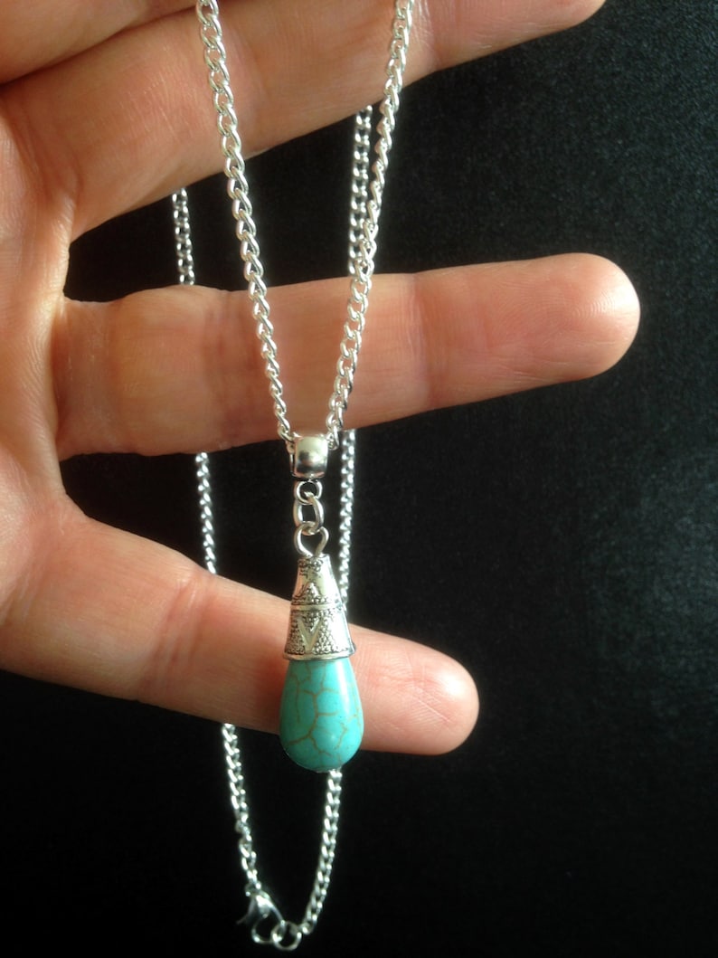 Puede incluir: Un collar de cadena de plata con un colgante de l&aacute;grima turquesa. El colgante tiene una tapa de plata con un dise&ntilde;o ornamentado.