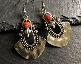 May include: Silver earrings with a fan-shaped design and a red stone bead. The earrings have a delicate, intricate design with small beads and a hook fastening.