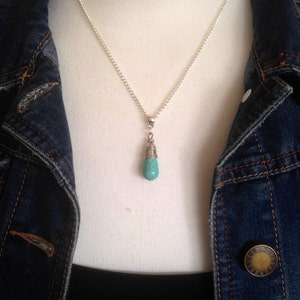 Puede incluir: Un collar de cadena de plata con un colgante de l&aacute;grima turquesa.