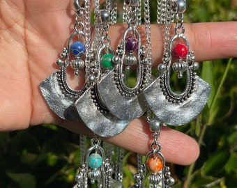 May include: Five silver necklaces with ornate pendants and colorful gemstone beads. Each pendant features a fan-shaped design with intricate details. The necklaces are displayed against a green background.