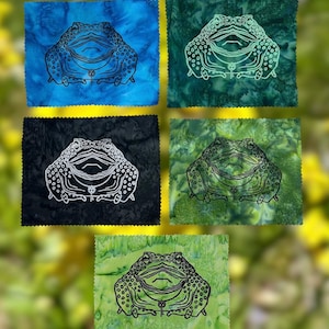 May include: Five rectangular fabric patches with pinked edges, each featuring a line art illustration of a toad wearing a key necklace. The patches come in blue, dark green, black, olive green, and light green, all with a mottled batik-style pattern.