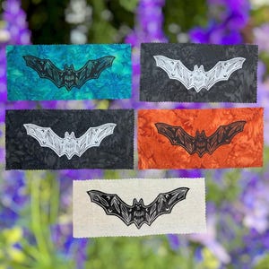 May include: Five rectangular fabric patches featuring a bat illustration with leaf and crescent moon wing patterns. The patches come in teal, black, white, and orange colors, each with pinked edges and a centered bat graphic in contrasting ink.