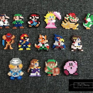 Può includere: Una collezione di 16 personaggi pixel art di videogiochi popolari, tra cui Mario, Luigi, Peach, Link e Kirby. Ogni personaggio è realizzato con perline di plastica colorate e misura circa 5 cm di altezza.