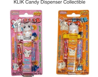 May include: Two vintage Hamtaro KLIK candy dispensers in original blister packaging. One is pink featuring Bijou, and the other is orange featuring Hamtaro. Each includes a character topper, a candy tube, and a roll of bubble gum candy.