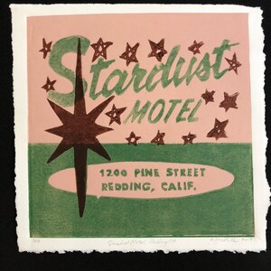 May include: A vintage-style illustration of a motel sign with the text "Stardust Motel" in green lettering on a pink background. The sign also includes a large brown star with a green outline and the address "1200 Pine Street Redding, Calif."
