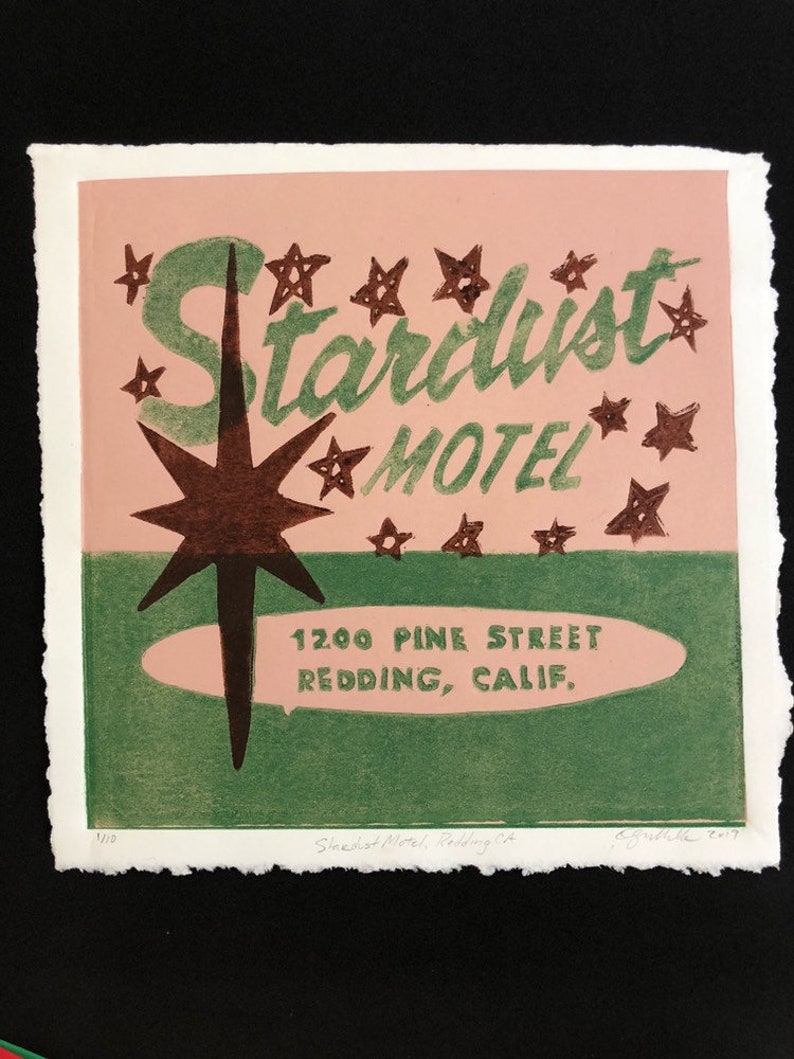May include: A vintage-style illustration of a motel sign with the text "Stardust Motel" in green lettering on a pink background. The sign also includes a large brown star with a green outline and the address "1200 Pine Street Redding, Calif."