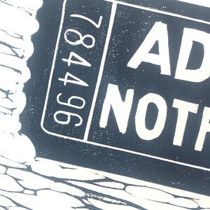 May include: Black and white image of a ticket with the text "ADMIT NOTHING" and the number "96487" printed on it.