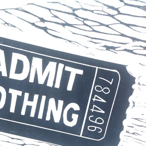 May include: A black and white ticket with the text "ADMIT ONE THING" and the number "964781" printed on it.