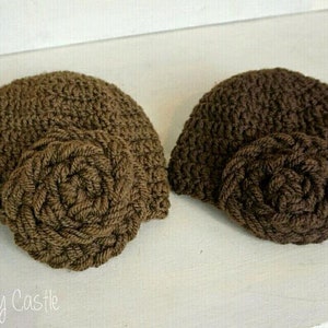 May include: Two brown crocheted hats with a large brown crocheted flower on the side of each hat.
