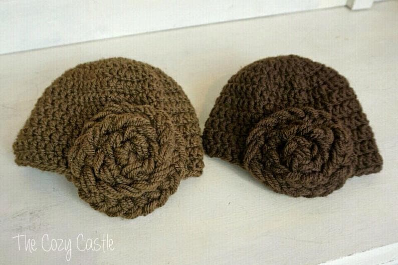May include: Two brown crocheted hats with a large brown crocheted flower on the side of each hat.