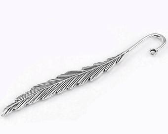May include: Silver feather bookmark with a curled end. The bookmark is detailed with lines to resemble a feather.