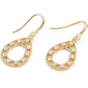 May include: A pair of gold teardrop earrings with a delicate openwork design and clear cubic zirconia stones.