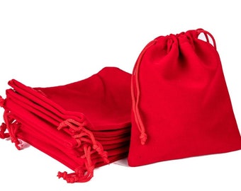 May include: A stack of ten red velvet drawstring pouches, with one pouch standing upright in front of the stack.