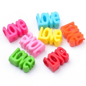 May include: Assortment of colorful plastic beads spelling out the word "love". The beads are in pink, blue, yellow, red, green, and orange.