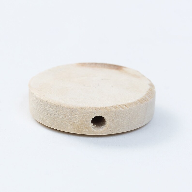 May include: A round, unfinished wooden disc with a hole in the center. The disc is light brown in color and has a smooth surface.