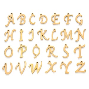 May include: A set of 26 gold-colored metal alphabet letter charms. Each letter is in a cursive script font and has a small hole at the top for attaching to a chain or bracelet.