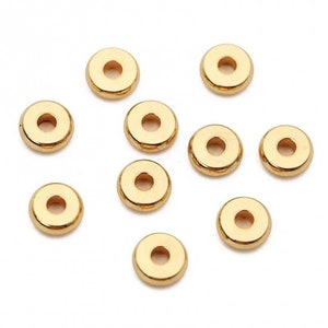 May include: Ten gold-colored metal spacer beads. The beads are round with a hole in the center.