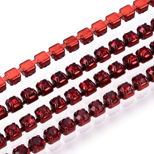 May include: Four rows of red rhinestone chain trim. The chain is made of metal and has a shiny finish. The rhinestones are square shaped and have a faceted design.