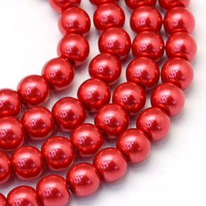 May include: A strand of red pearl beads. The beads are round and have a smooth, glossy finish.