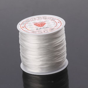 May include: A spool of white elastic string labeled "Strong & Stretchy" and "Crystal String 100%".