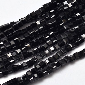 May include: A strand of black square-shaped beads. The beads are faceted and have a glossy finish.