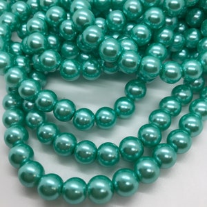 May include: A strand of teal green pearl beads. The beads are round and have a smooth, glossy finish.