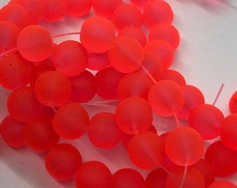 Könnte beinhalten: Eine Strähne aus leuchtend pinken, gefrosteten Glasperlen. Die Perlen sind rund und haben eine matte Oberfläche.