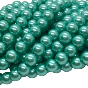 May include: A pile of teal green pearl beads. The beads are round and have a smooth, glossy finish.