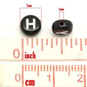 May include: Black plastic letter beads with a white letter "H" on one side and a white letter "Y" on the other side. The beads are 7 mm in diameter and have a 1 mm hole.