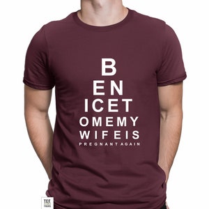 May include: Burgundy t-shirt with a white eye chart design that reads "B E N I C E T O M E M Y W I F E I S P R E G N A N T A G A I N"