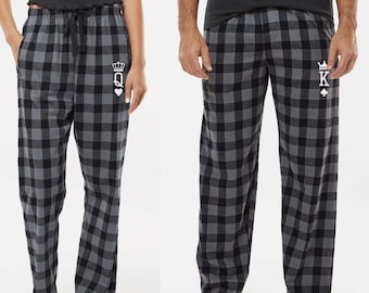 May include: A pair of black and grey plaid pyjama trousers with a white queen of hearts symbol on the left leg and a white king of spades symbol on the right leg.