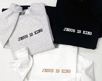 May include: Three sweatshirts with the text "JESUS IS KING" in black and white lettering. One sweatshirt is gray, one is black, and one is white with gold lettering.