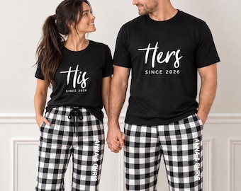 May include: Two black t-shirts with white text reading His Since 2026 and Hers Since 2026, paired with black and white buffalo plaid pajama pants. The pants feature the white text Anna & Chris printed vertically along the left leg.