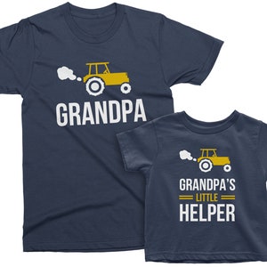 May include: Two navy blue t-shirts with a yellow tractor graphic and the text "Grandpa" and "Grandpa's Little Helper".