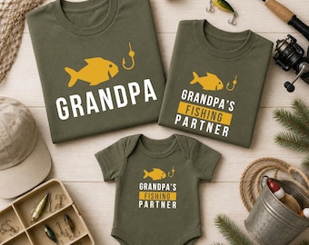 May include: Olive green t-shirts and a onesie with fishing-themed graphics. The shirts read "GRANDPA" and "GRANDPA'S FISHING PARTNER" with a yellow fish and hook design. Fishing gear and accessories surround the shirts.