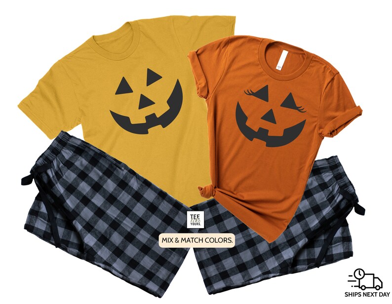 May include: A matching set of two t-shirts with a black jack-o'-lantern face design. One shirt is orange and the other is yellow. The shirts are paired with black and gray plaid pajama pants.