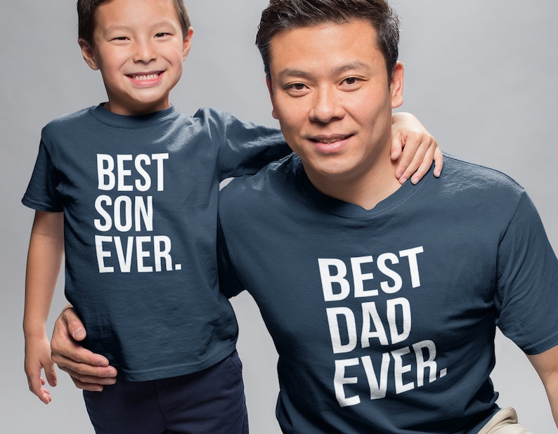 May include: A father and son wearing matching navy blue t-shirts. The father's shirt says "BEST DAD EVER." The son's shirt says "BEST SON EVER."