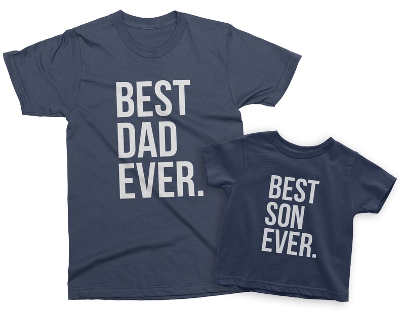 May include: Two navy blue t-shirts with white text. The larger shirt says "Best Dad Ever." The smaller shirt says "Best Son Ever."