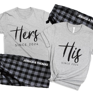 May include: A set of matching gray t-shirts with the words "Hers" and "His" and the year "2024" printed on them. The shirts are paired with black and gray plaid pajama pants with the text "Jessica & Thomas" printed on them.