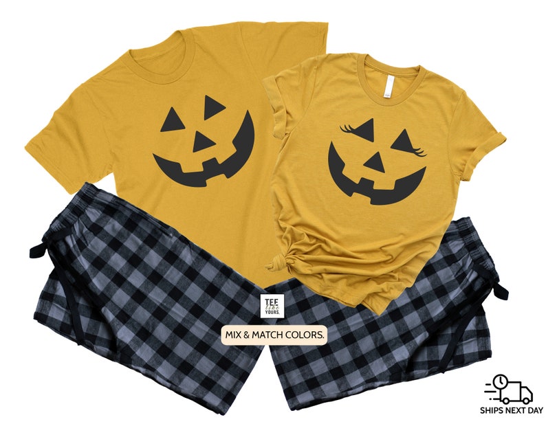 May include: A set of two mustard yellow t-shirts with a black jack-o'-lantern face graphic. One shirt has eyelashes on the jack-o'-lantern. The shirts are paired with black and gray plaid pajama pants.