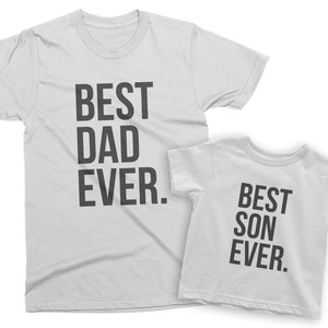 May include: Two white t-shirts with black text. The larger shirt says "BEST DAD EVER." The smaller shirt says "BEST SON EVER."
