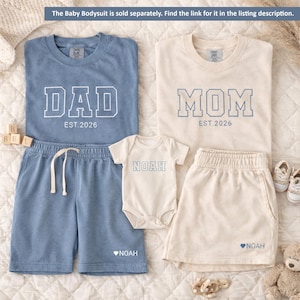 Peut inclure: Ensemble de v&ecirc;tements assortis pour la famille, avec des hauts et des shorts bleus et cr&egrave;me. Les chemises affichent "DAD" et "MOM" avec "EST.2026". L'ensemble comprend un body et un short pour b&eacute;b&eacute;, tous deux avec le nom "NOAH". Un c&oelig;ur est &agrave; c&ocirc;t&eacute; du nom "NOAH" sur le short.