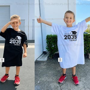 May include: Two children's t-shirts, one black and one white, each with the text "Class of 2039" and a graduation cap graphic. The name "Thomas" is printed below the year. Both children are wearing red sneakers.
