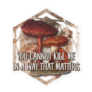 Könnte beinhalten: Ein sechseckiger Aufkleber mit einem Grunge-Hintergrund, der drei Pilze in Braun- und Rottönen zeigt. Der Text "YOU CANNOT KILL ME IN A WAY THAT MATTERS" ist in Weiß auf dem Aufkleber gedruckt.