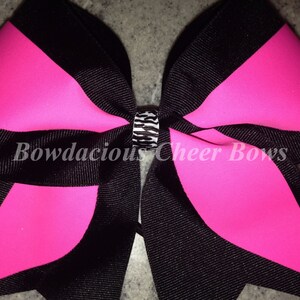 May include: A large black and hot pink cheer bow with a black and white zebra print center.