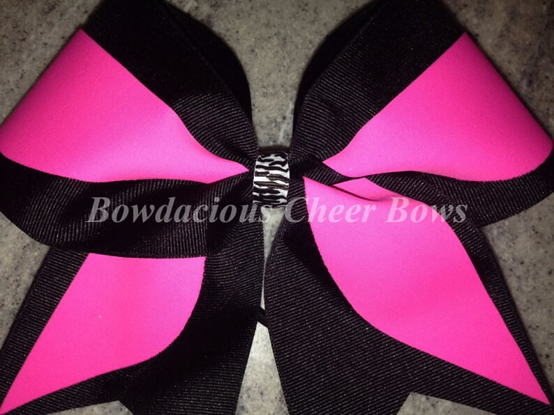 May include: A large black and hot pink cheer bow with a black and white zebra print center.