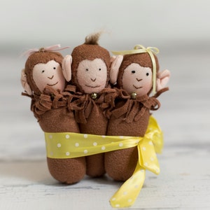 May include: Three brown monkey plush toys with yellow polka dot ribbon tied around them. The monkeys have brown fur, brown eyes, and pink noses.