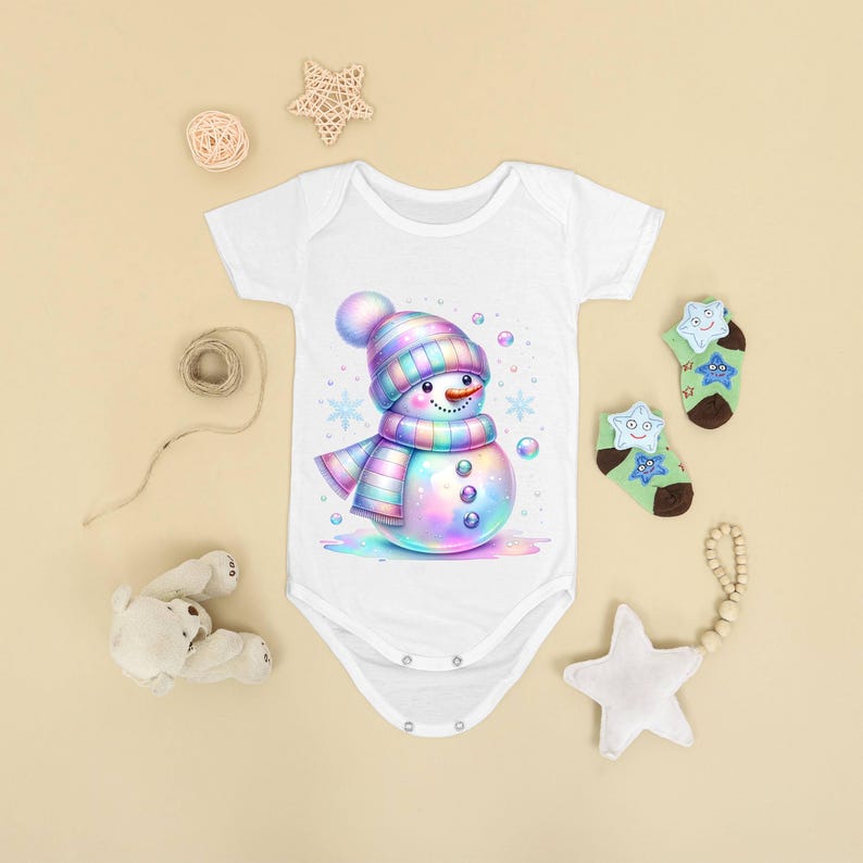 Puede incluir: Body de beb&eacute; blanco con una ilustraci&oacute;n de un mu&ntilde;eco de nieve colorido. El mu&ntilde;eco de nieve tiene un gorro y una bufanda a rayas, con una nariz de zanahoria y ojos de bot&oacute;n. Copos de nieve y burbujas rodean al mu&ntilde;eco de nieve. Tambi&eacute;n hay dos pares de calcetines verdes con dise&ntilde;os de estrellas.